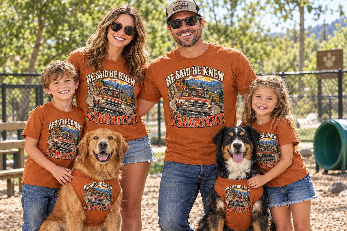 Family and two dogs wearing matching He Said He Knew a Shortcut T-shirts at a dog park