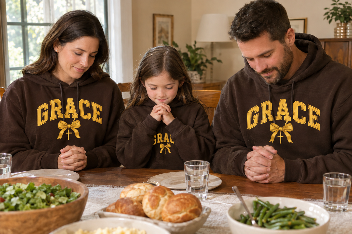Family in brown GRACE hoodies praying together before dinner